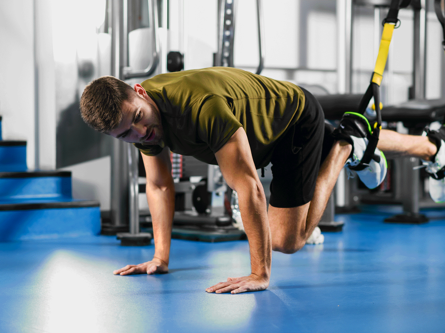 Person macht eine Fitnessübung auf dem Boden in einem Trainingsraum.