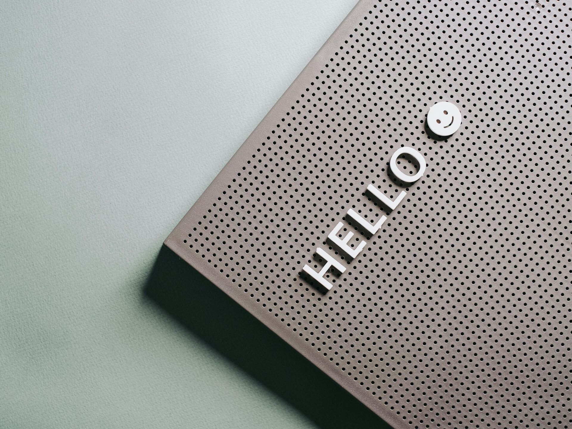 Detailaufnahme einer Lochblechfläche mit dem Schriftzug „HELLO“ und einem kleinen Smiley.