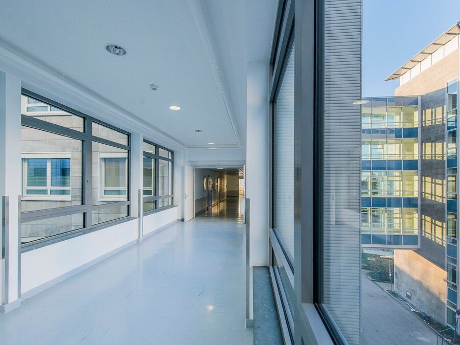 Heller, moderner Flur mit großen Fenstern und glänzendem Boden in einem Büro- oder Klinikgebäude.