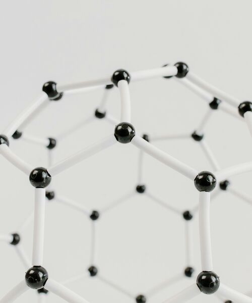 Abstraktes Modell einer Molekülstruktur aus weißen Stäben und schwarzen Verbindungspunkten auf hellem Hintergrund.