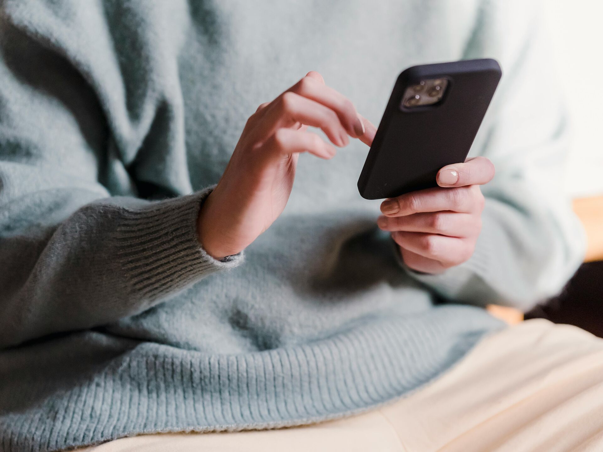 Nahaufnahme einer Person, die auf ihrem Smartphone tippt.