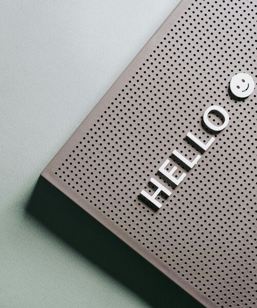 Detailaufnahme einer Lochblechfläche mit dem Schriftzug „HELLO“ und einem kleinen Smiley.