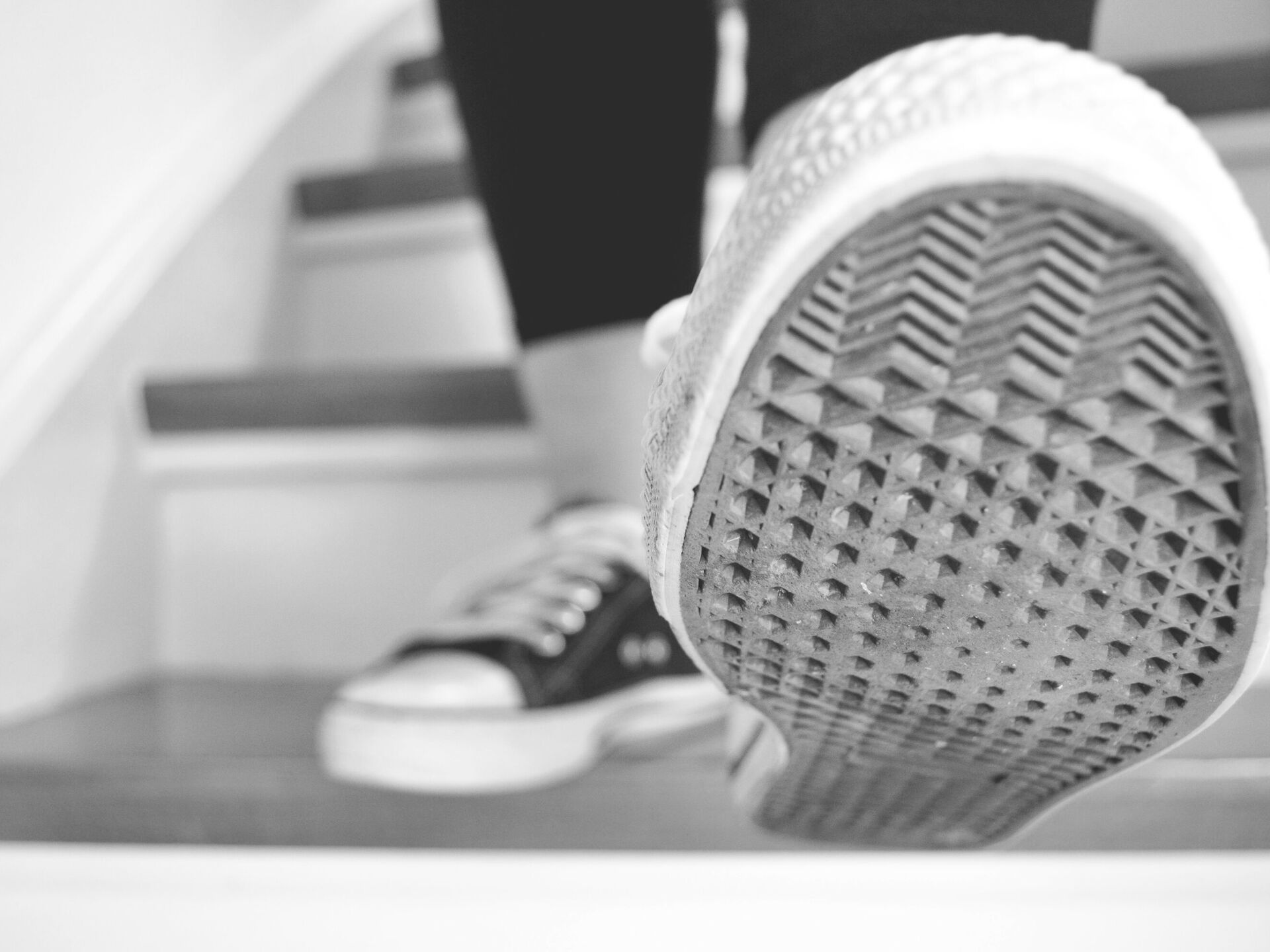 Nahaufnahme einer Person, die eine Treppe hinaufgeht, mit Fokus auf die Sohle eines Sneakers.
